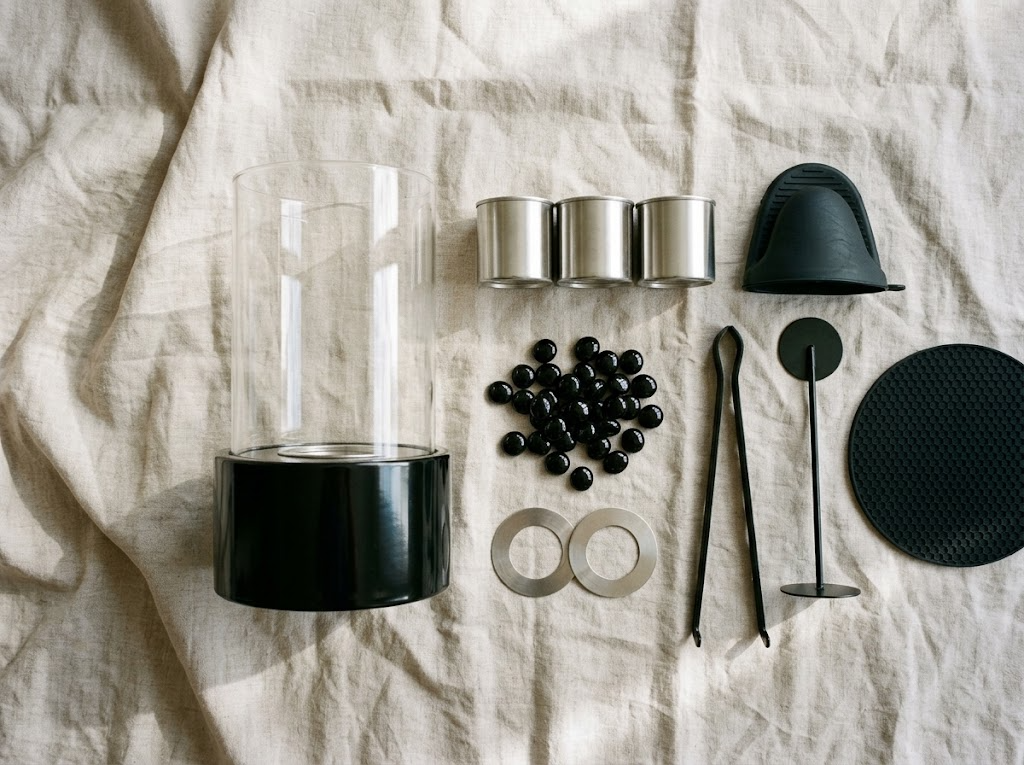 Contenu du kit complet : cheminée cylindre de verre, trois réservoirs inox, galets noirs, bagues, pince, gant, éteignoir et dessous de protection